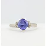 A 14ct white gold (stamped 14K) ring set with a cushion cut tanzanite and diamonds, (N).