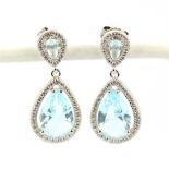 A pair of 925 silver drop earrings set with pear cut blue stones surrounded by cubic zirconias, L.