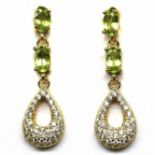 A pair of gold on 925 silver drop earrings set with oval cut peridots and white stones, L. 2.6cm.