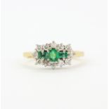 A yellow metal (tested minimum 9ct gold) ring set with baguette cut emeralds surrounded by diamonds,