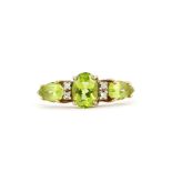 A 9ct yellow gold ring set with an oval cut peridot, diamonds and pear cut peridot set shoulders, (