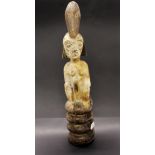 A rare African carved wooden tribal figure of a woman seated on a coiled snake with the snake's head