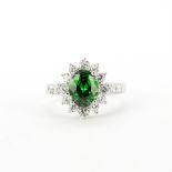 A large 925 silver cluster ring set with an oval cut green stone surrounded by cubic zirconias, (