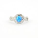 A 925 silver ring set with a oval cabochon cut synthetic opal surrounded by cubic zirconias, (R ).