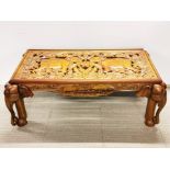 An Oriental carved teak coffee table with elephant head legs, 69 x 130cm.