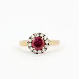 A yellow metal (tested minimum 14ct gold) cluster ring set with a round cut red stone surrounded