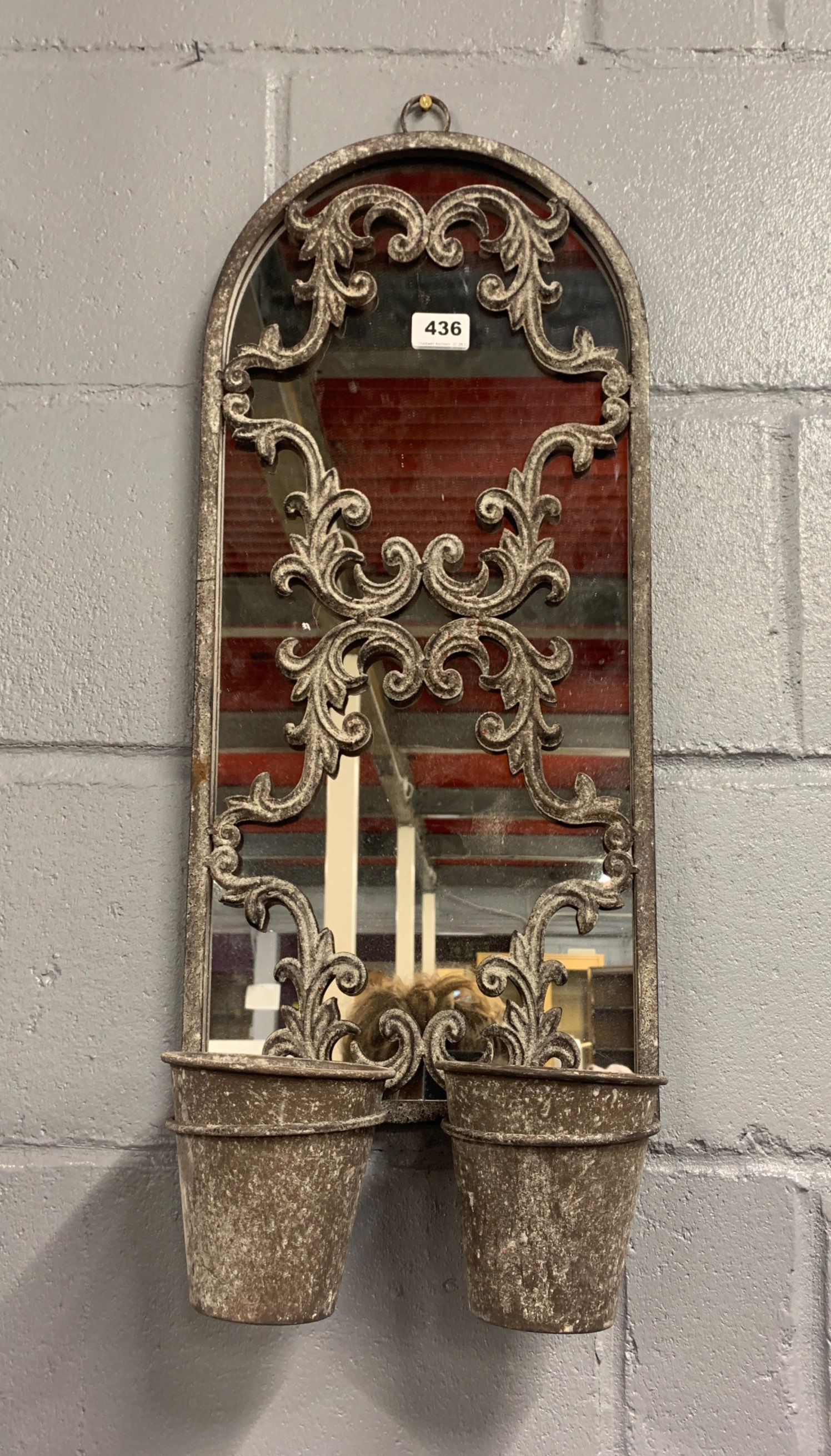 A metal framed garden mirror with two pot holders, W. 59cm, H. 70cm.