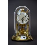 A brass Koma torsion mantle clock under dome, H. 22cm.