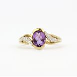 A hallmarked 9ct yellow gold ring set with an oval cut amethyst and diamonds, (P).