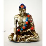 A Tibetan silvered bronze and enamelled stone set figure of a seated Buddha, H. 9cm.