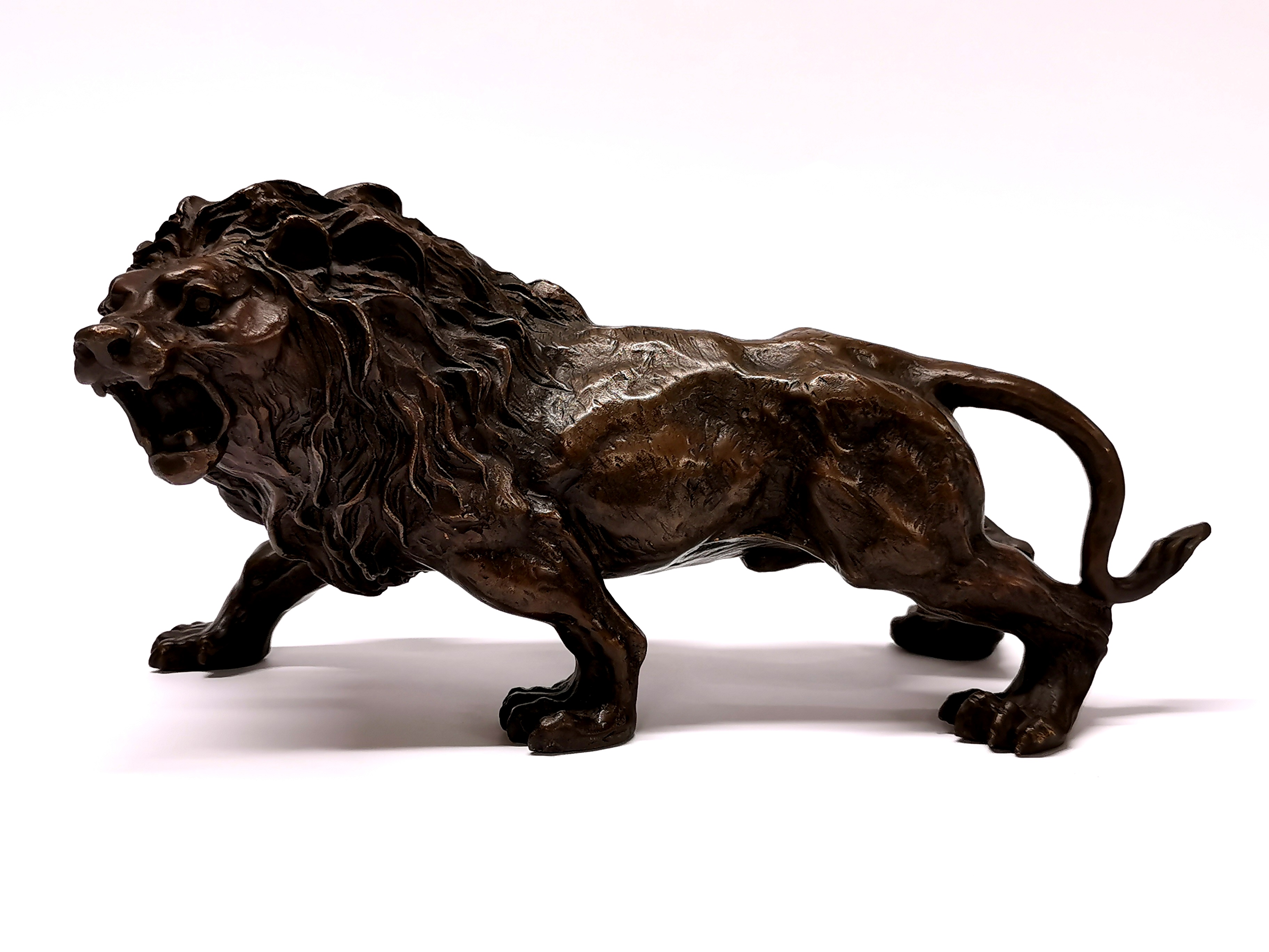 A cast bronze figure of a lion, H. 15cm, L. 30cm.