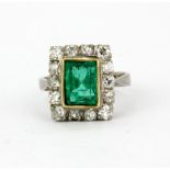 An 18ct white gold (stamped 18ct) ring set with a large emerald cut emerald surrounded by