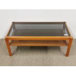 A 1970's teak coffee table with smoked glass top, 86 x 43 x 37cm.