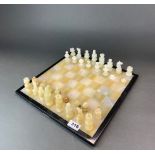 A polished onyx chess set and board, king H. 7.5cm, board size 35 x 35cm.