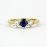 An 18ct yellow gold ring set with an oval cut sapphire and brilliant cut diamonds, (K).