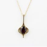 A hallmarked 9ct yellow gold drop pendant set with an oval cut garnet on a 9ct yellow gold chain, L.