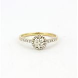 A hallmarked 9ct yellow gold halo ring set with brilliant cut diamonds and diamond set shoulders, (