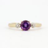 A hallmarked 9ct yellow gold ring set with a round cut amethyst and diamond set shoulders, (O.5).