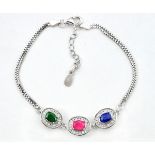 A 925 silver bracelet set with oval cut ruby, sapphire and emerald surrounded by white stones, L.