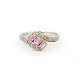 A hallmarked 9ct white gold crossover ring set with oval cut pink sapphires and diamonds, (P.5).