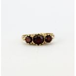 A hallmarked 9ct yellow gold ring set with round cut garnets. Shank A/F.