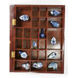 A wooden wall mounted display cabinet containing a quantity of Chinese snuff bottles.