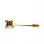 An antique yellow metal stick pin set with an oval cut tourmaline and seed pearls, L. 5.3.