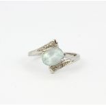 A hallmarked 9ct white gold (worn hallmark) crossover style ring set with an oval cut aquamarine, (