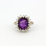 A hallmarked 9ct yellow gold ring set with a large emerald cut amethyst surrounded by cubic