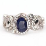 A 925 silver ring set with an oval cut sapphire and white stones, (K).