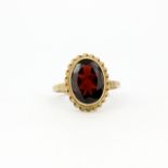 A hallmarked 9ct yellow gold ring set with a large oval cut garnet, L. 1cm, (Q.5).