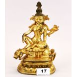 A Tibetan gilt bronze figure of a seated guardian deity, H. 20.5cm.