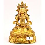 A Tibetan gilt bronze figure of a seated crowned Buddha with detailed hand painted face, H. 26cm.