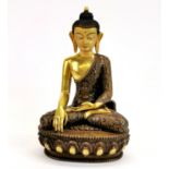 A Temple quality Tibetan bronze figure of a seated Buddha with hand painted face, H. 22cm.