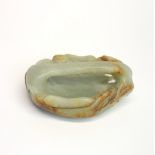A Chinese carved celadon and russet jade guardian mask buckle.