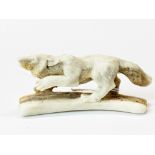 A hand carved antler in the form of a running wolf.