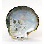 A hand carved black lip oyster mother of pearl shell with skull, with perspex display stand.