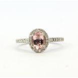 An 18ct white gold ring set with an oval cut morganite, approx. 0.82ct, surrounded by diamonds and