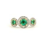 A hallmarked 18ct yellow and white gold triple halo ring set with round cut emeralds surrounded by