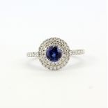 A 950 platinum ring set with a round cut sapphire, approx. 0.60ct, surrounded by diamonds and