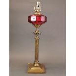 A 19th century gilt brass and ruby glass column oil lamp converted for electricity, H. 56cm.