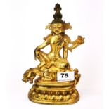 A Tibetan gilt bronze figure of a seated guardian deity, H. 20.5cm.