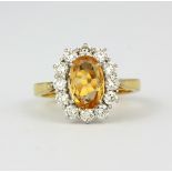 A hallmarked 18ct yellow gold cluster ring set with a large oval cut orange topaz, approx. 1.67ct,