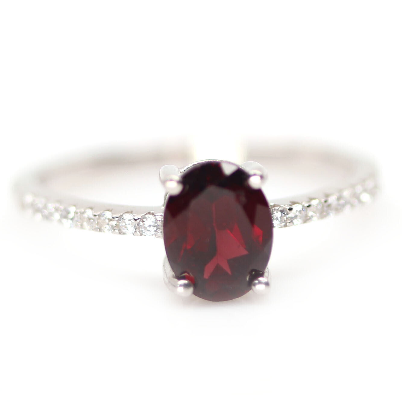 A 925 silver ring set with an oval cut garnet and white stone set shoulders, (N.5).