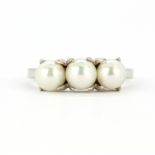 A 10ct white gold (stamped 10K) ring set with three cultured pearls, (M).