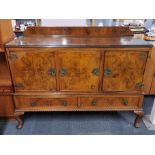 A plate glass topped burr walnut veneered cellarette sideboard with metal hinges and carved