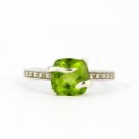 A hallmarked 9ct white gold solitaire ring set with a large cushion cut peridot with diamond set
