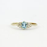 A hallmarked 9ct yellow gold ring set with an oval cut blue topaz and diamonds, (O.5).