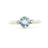 A hallmarked 9ct white gold ring set a round cut aquamarine and diamonds, (N).