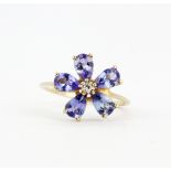 A 10ct yellow gold (stamped 10k) flower shaped ring set with a diamond and pear cut tanzanites, (N.
